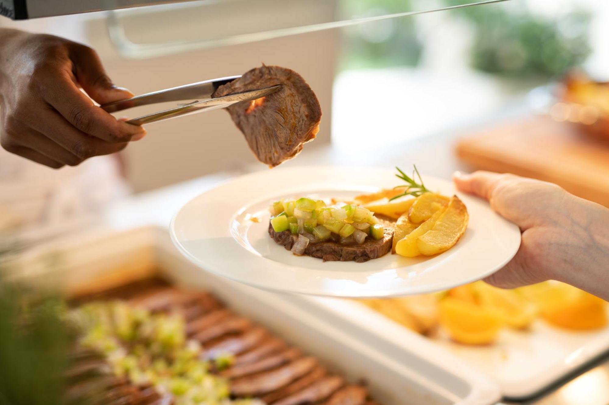 Grand Hotel רימיני מראה חיצוני תמונה A server using a pair of tongs to serve a steak